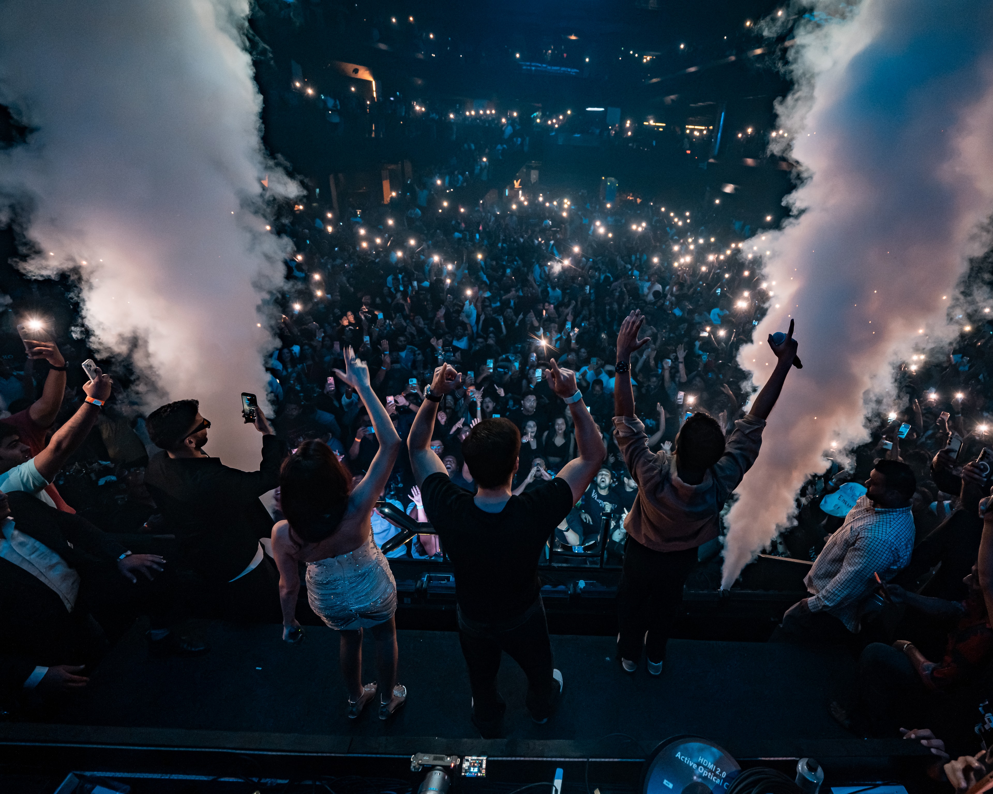 Looking out over a crowd of phone lights between two smoke cannons