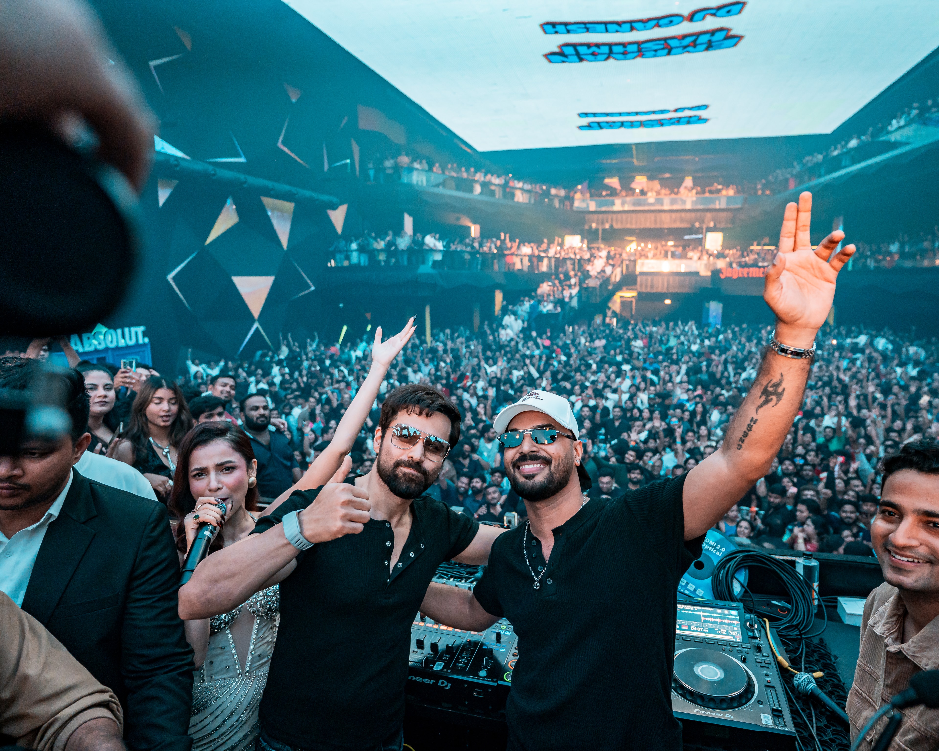 DJ Ganesh and Emraan Hashmi at the decks, arms up in front of a packed club